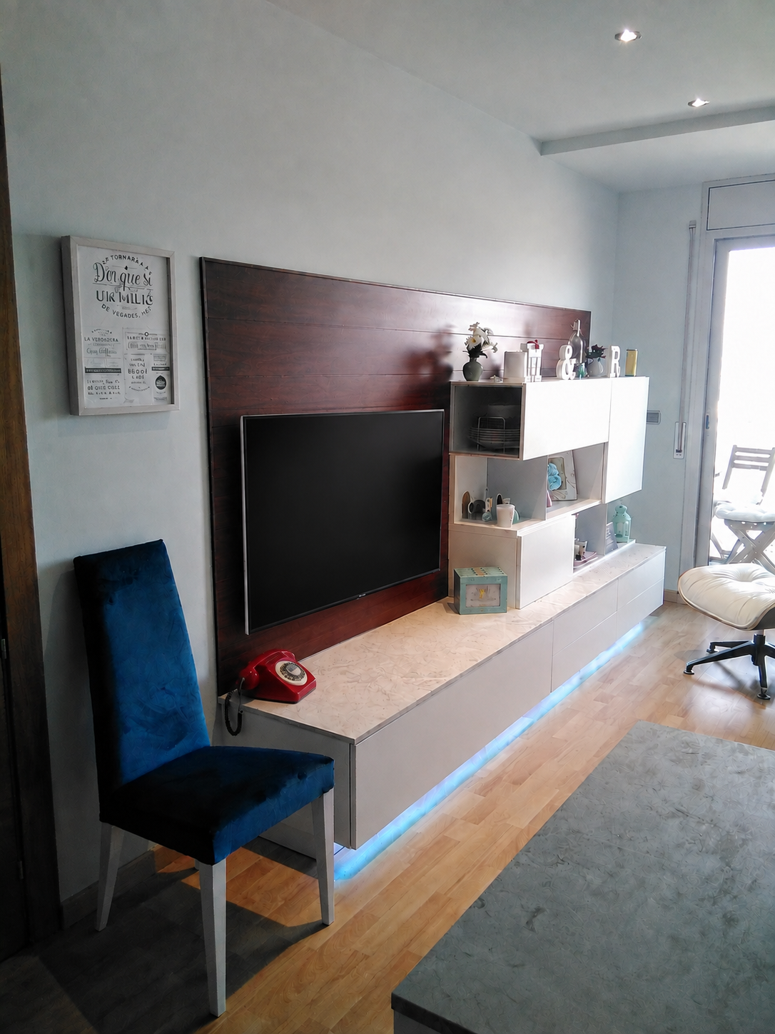 Televisor gran penjat al plafó de fusta i composició d’emmagatzematge del mini apartament