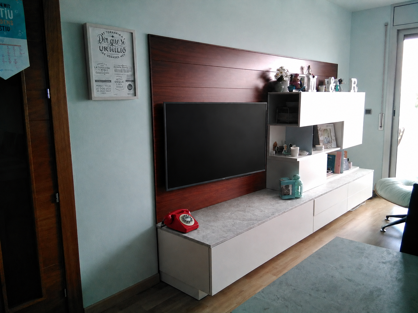 Vista de la sala amb un televisor gran penjat al plafó de fusta